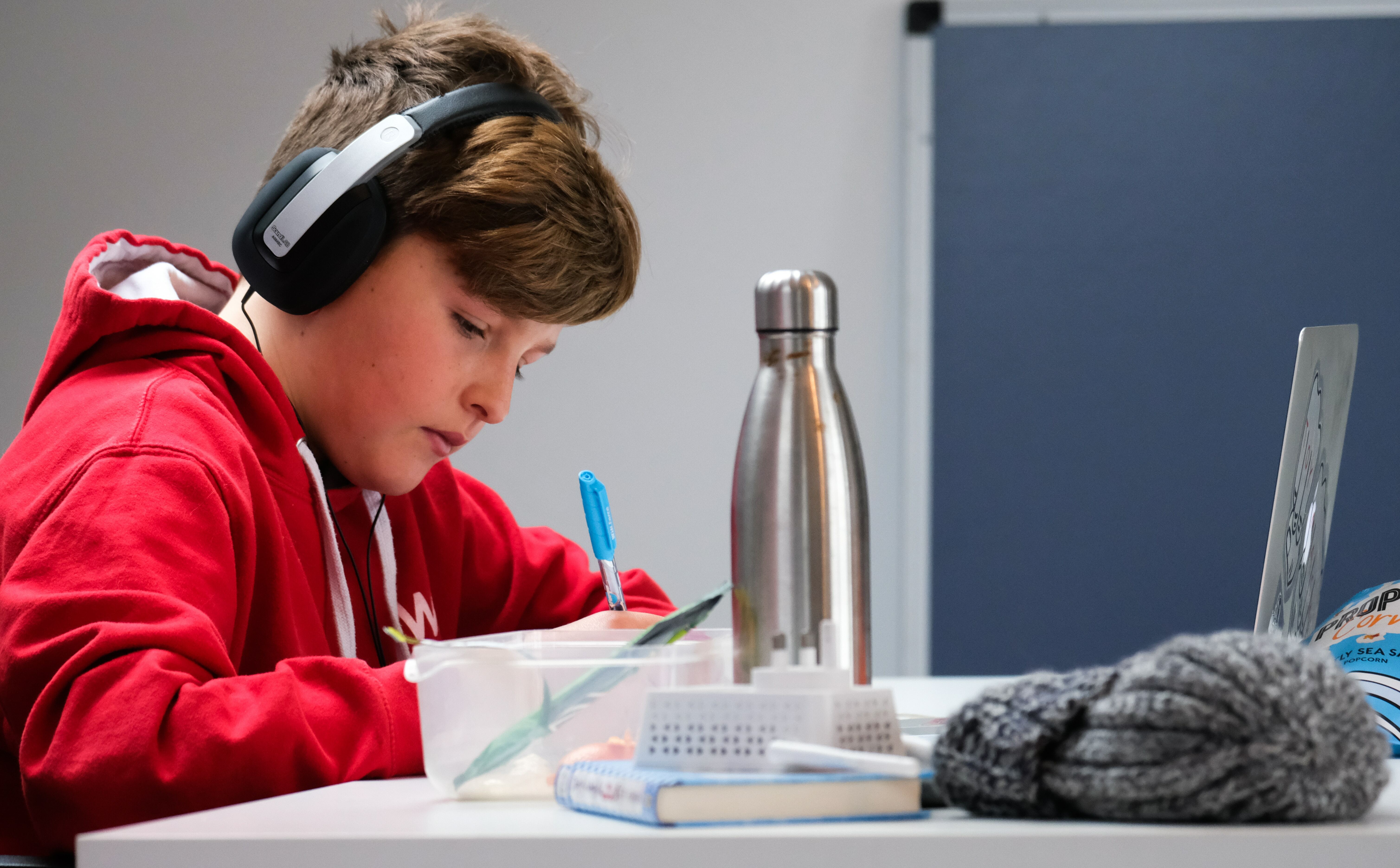 A child wearing a red hoodie writing