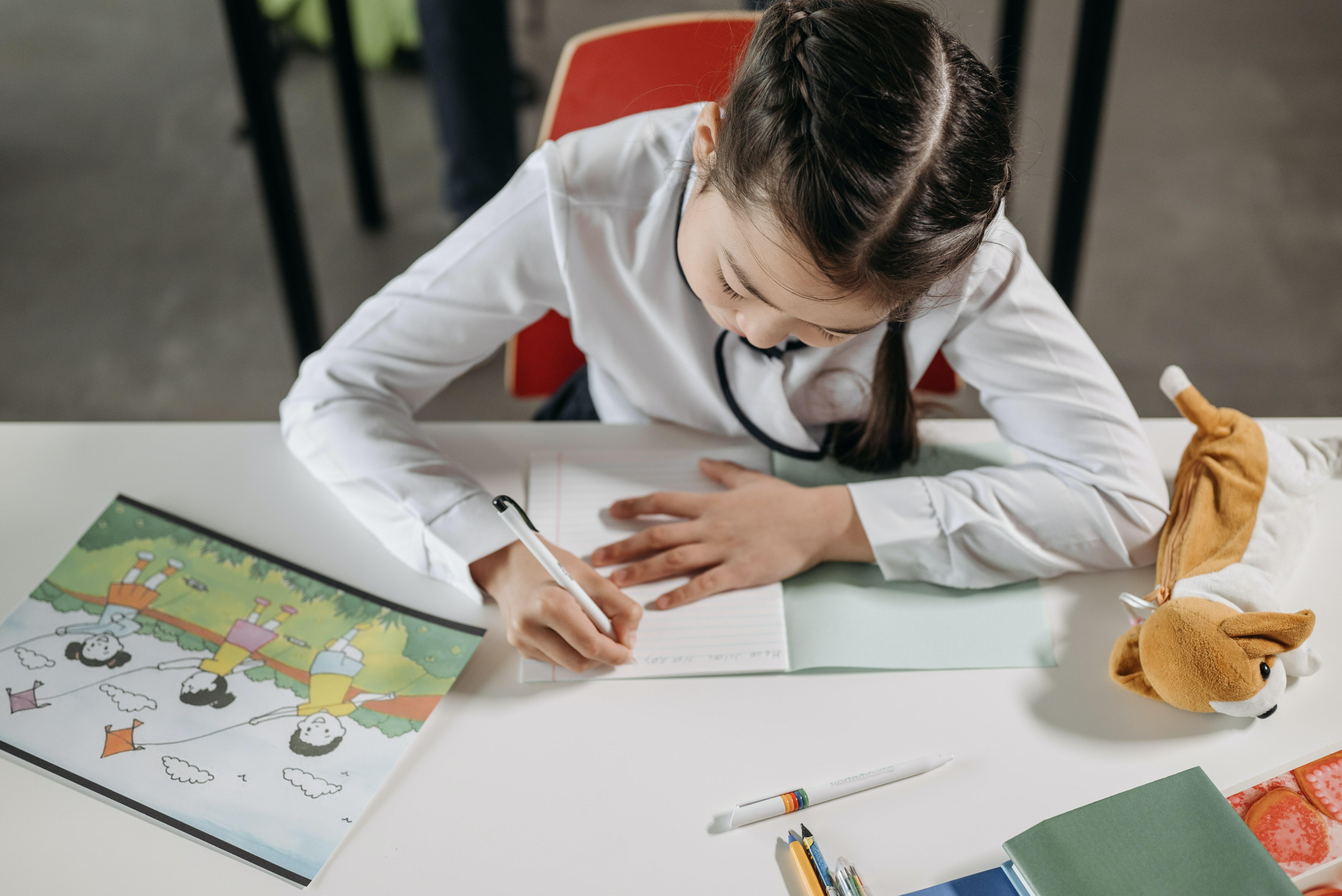 A child writing while sitting on a chair