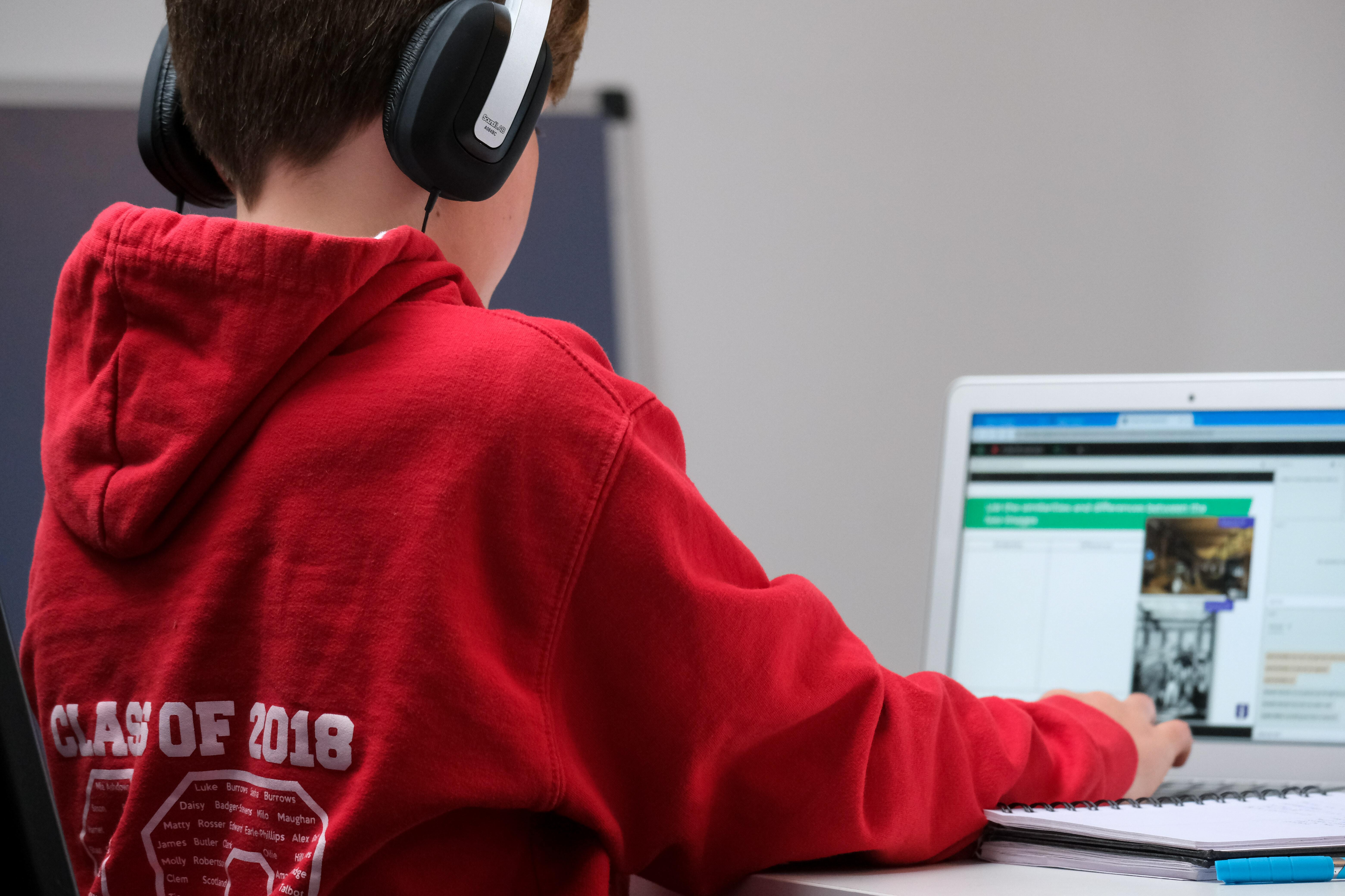 A child wearing headphones pressing a laptop