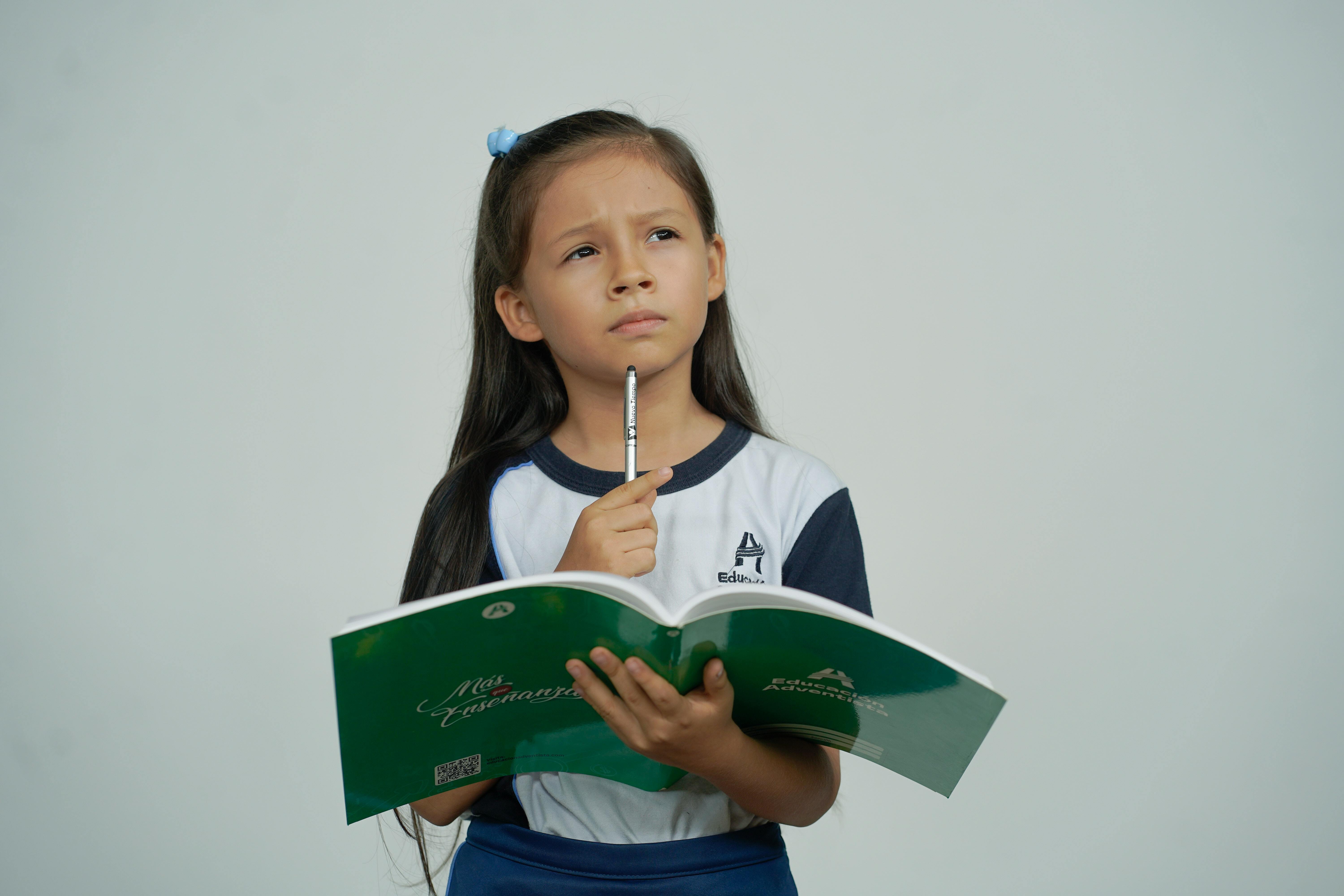 A female child holding a book while thinking