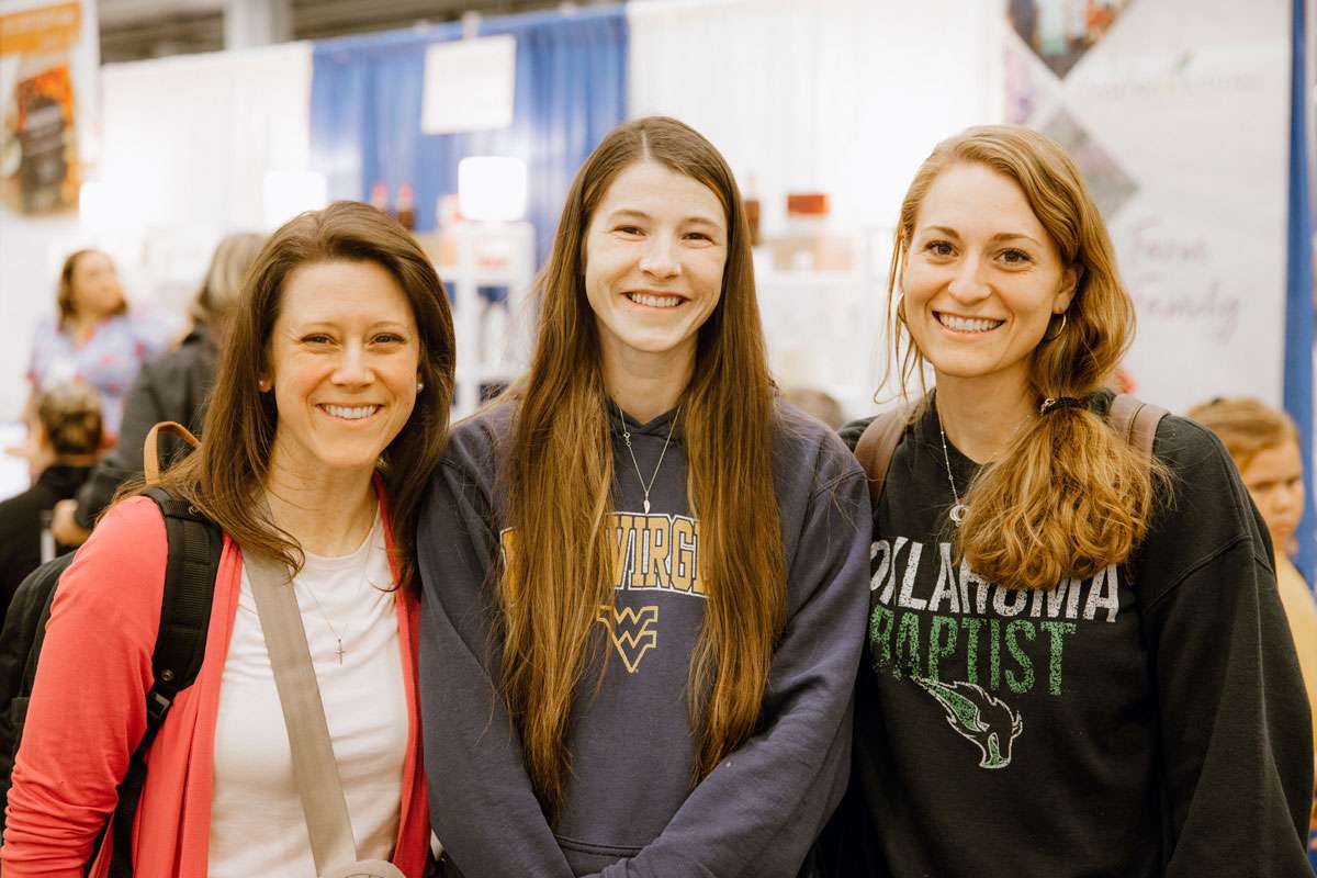 Three young female attendees smiling together at Convention