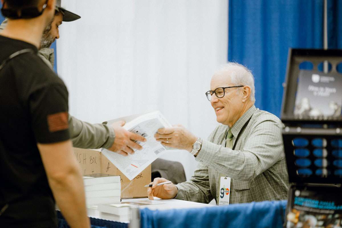 An exhibitor handing a brochure to an attendee at a convention booth