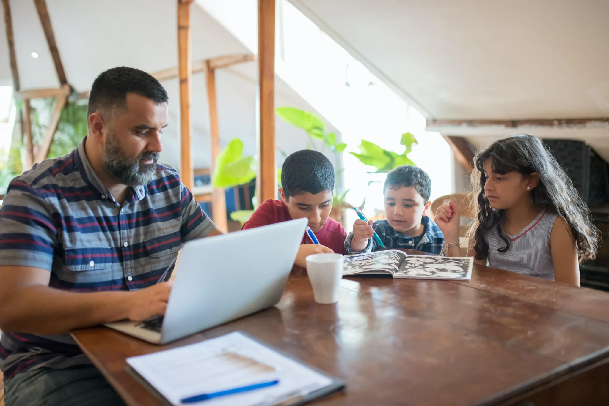 A father pressing laptop beside his kids