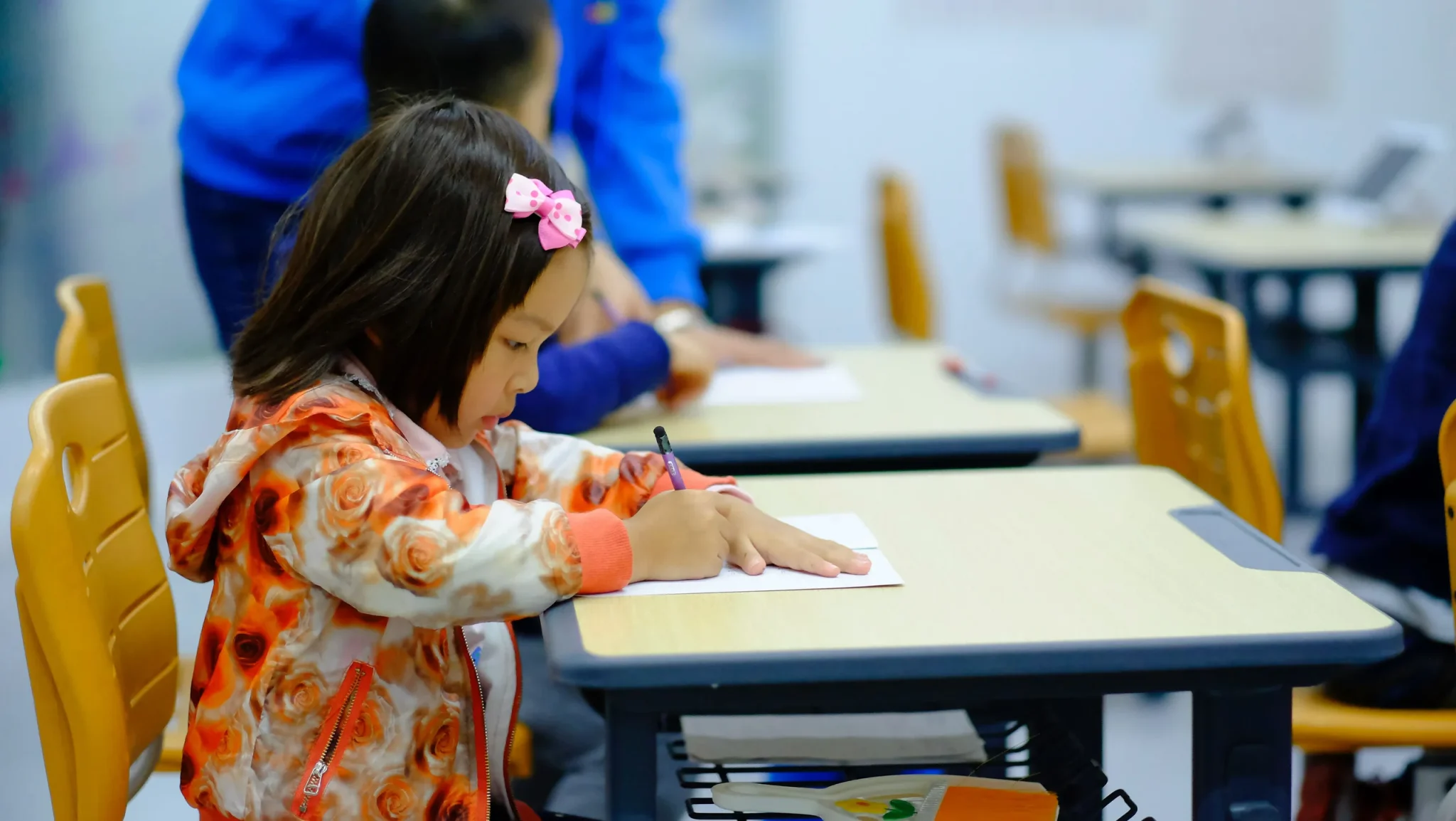 Little child writing on a paper placed on the desk