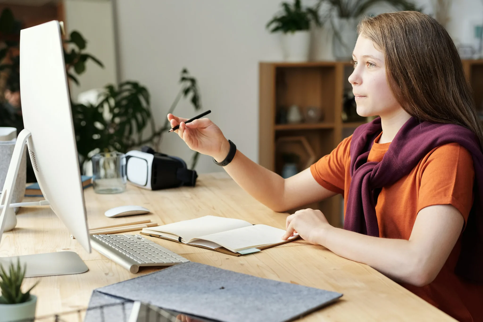 A girl holding a pen in front of a computer screen