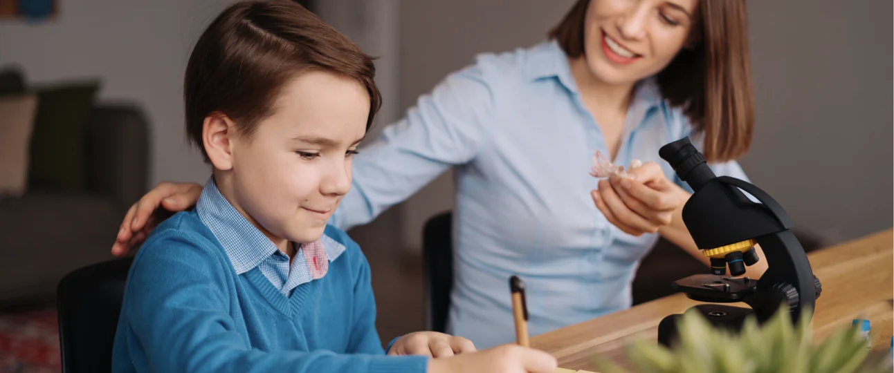 boy writes woman pats his back microscope