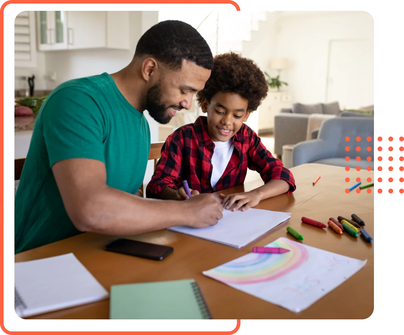 A father and his young son sitting at a dining table smiling and coloring with crayons on paper during a homeschool art lesson