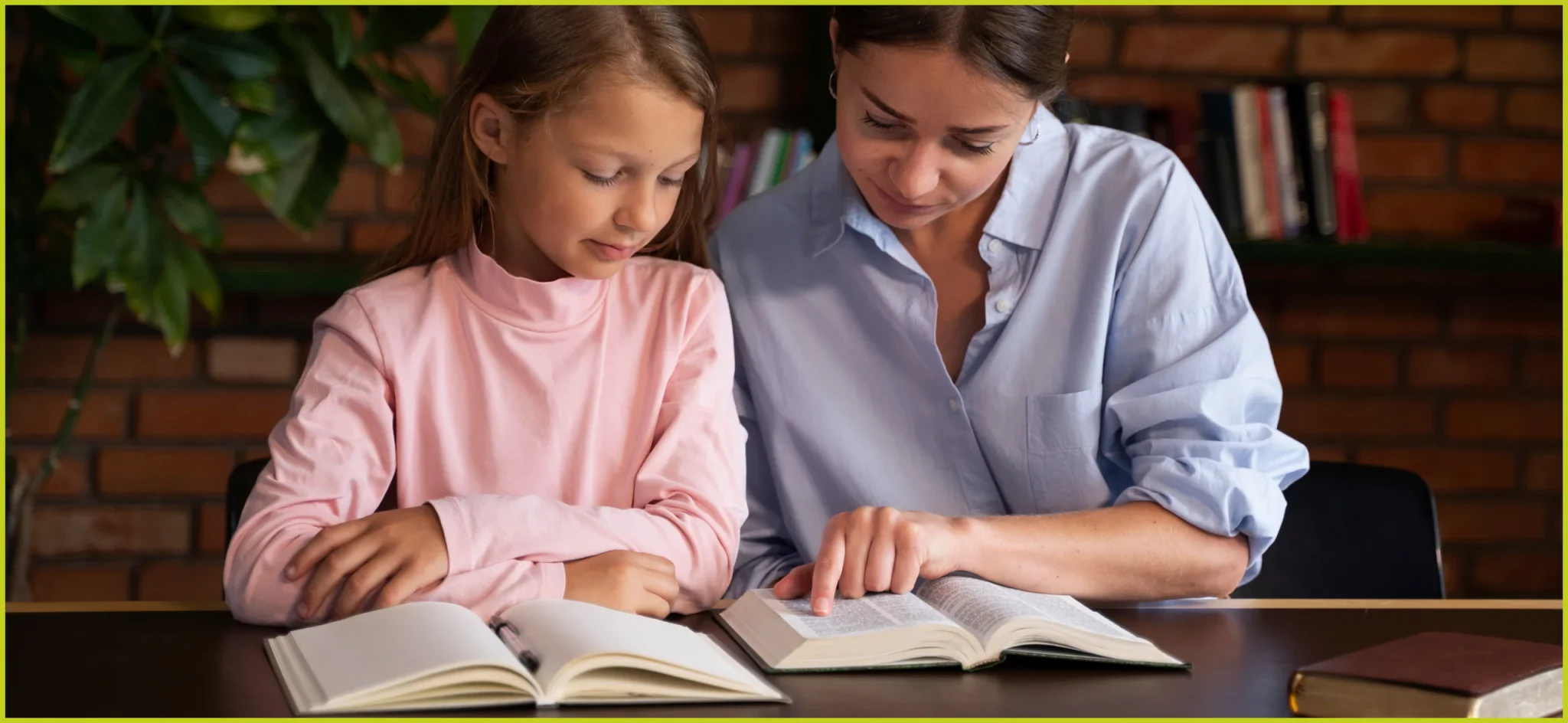 A mother pointing to an open textbook while reading with her young daughter at a wooden table