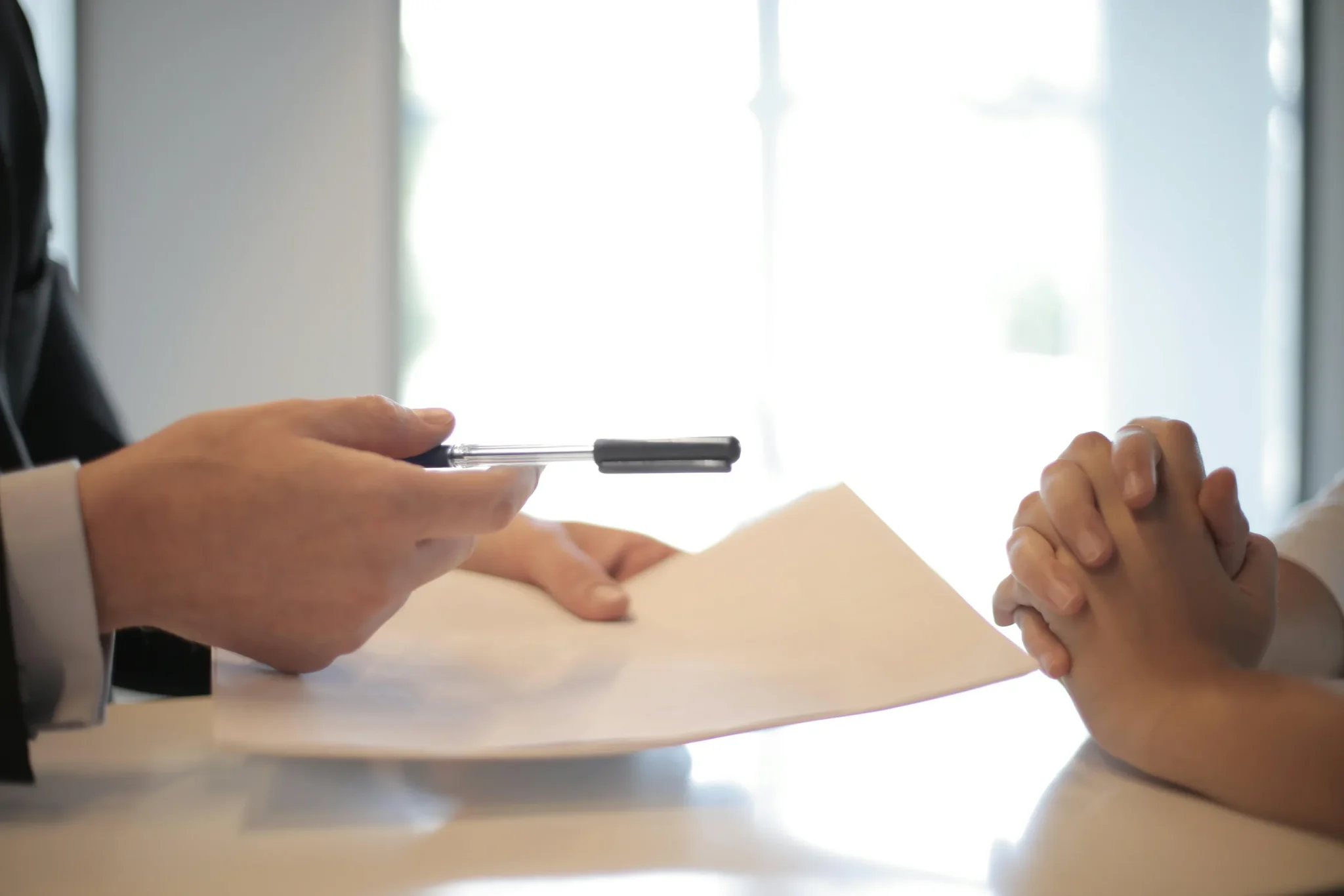 A person offering another a pen and a letter