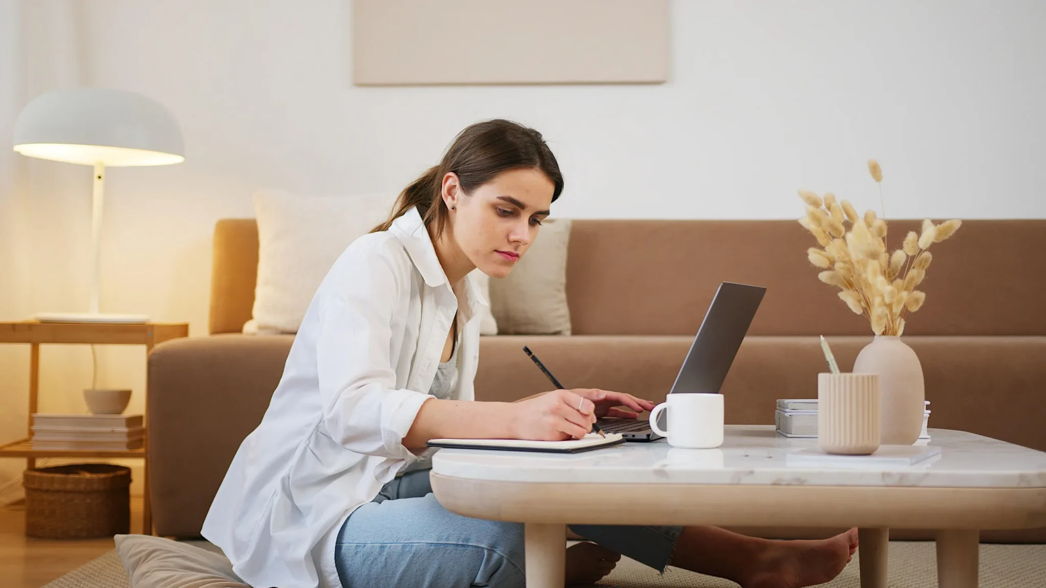 A lady writing in front of her laptop