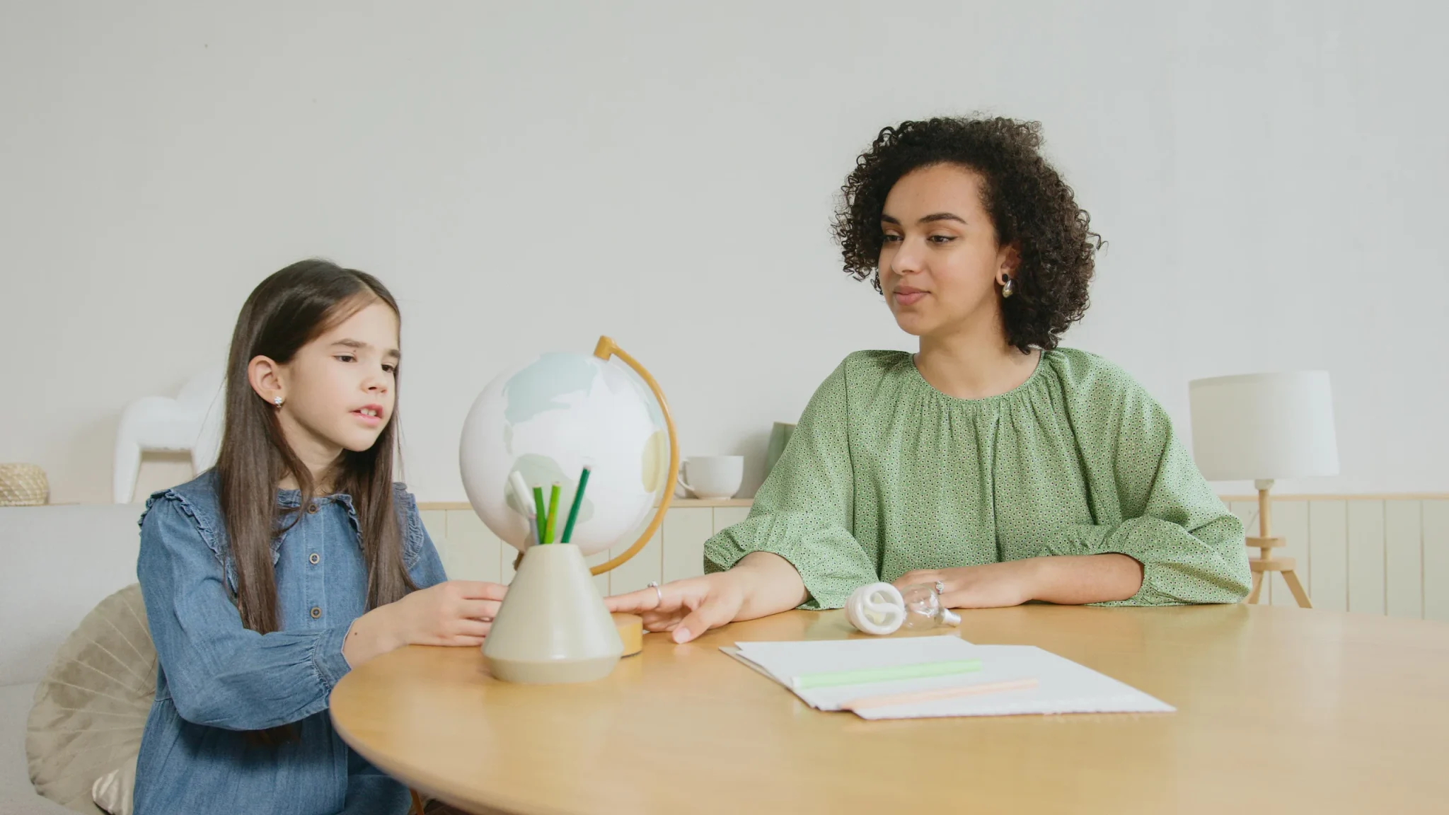 A woman showing a girl a globe